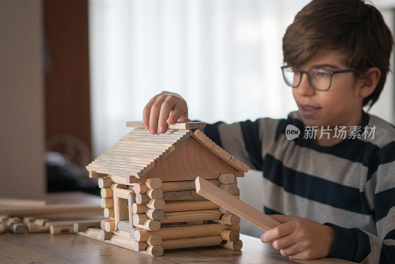 快乐的小男孩玩着木头房子