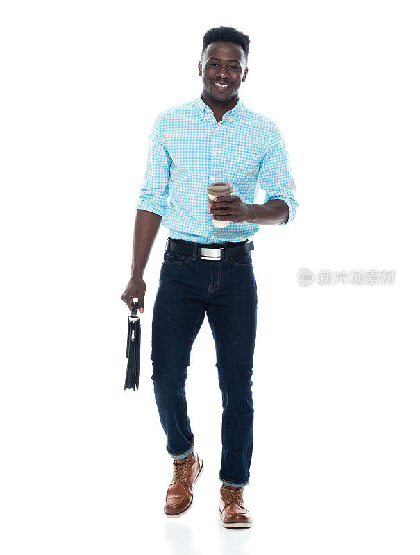 非洲裔男性穿着牛仔裤，拿着公文包走在白色背景前