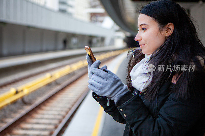 年轻女子在地铁站用手机储存照片