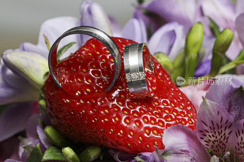 两枚结婚戒指戴在一束兰花上的草莓上