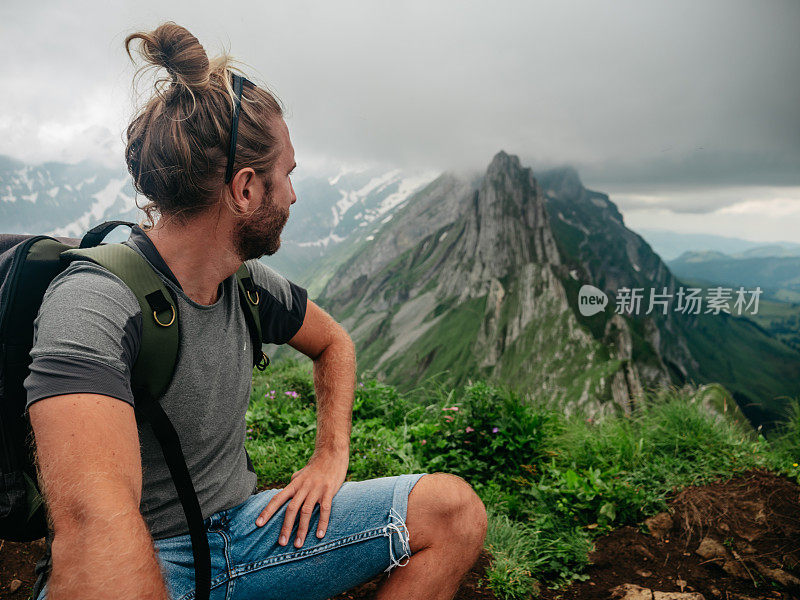 一名男子在瑞士徒步旅行，然后停下来看风景