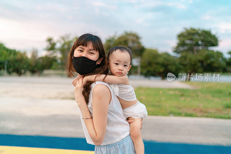 亚洲母亲照顾她的孩子，同时在户外探索冠状病毒大流行