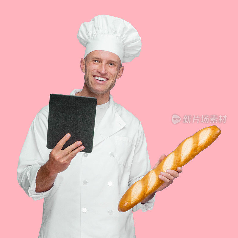 白人男性面包师在有色背景前穿着制服，手持法棍，使用触摸屏