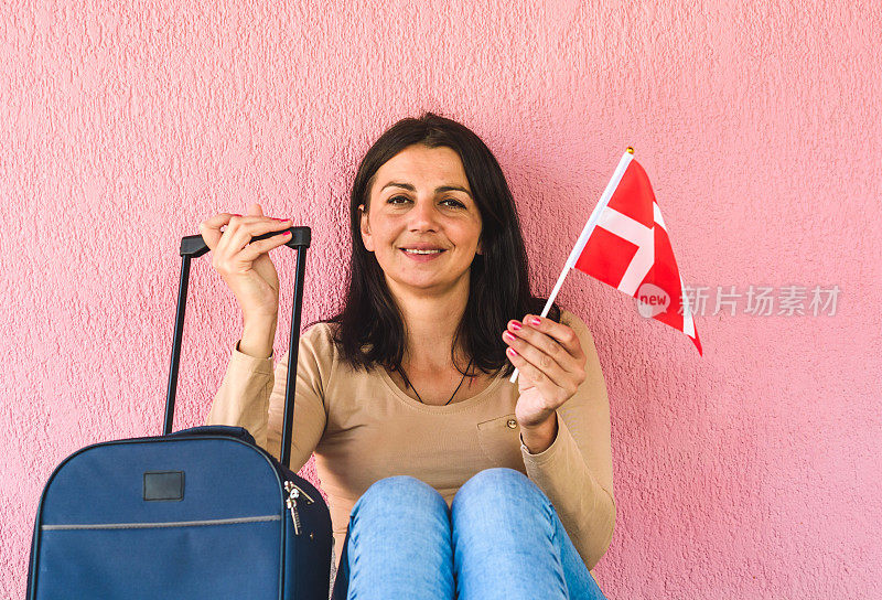 拿着旅行袋和丹麦国旗的女人