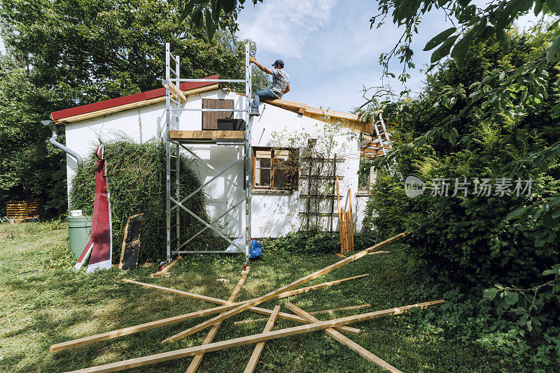 建筑工人坐在不完整的屋顶和木板在后院