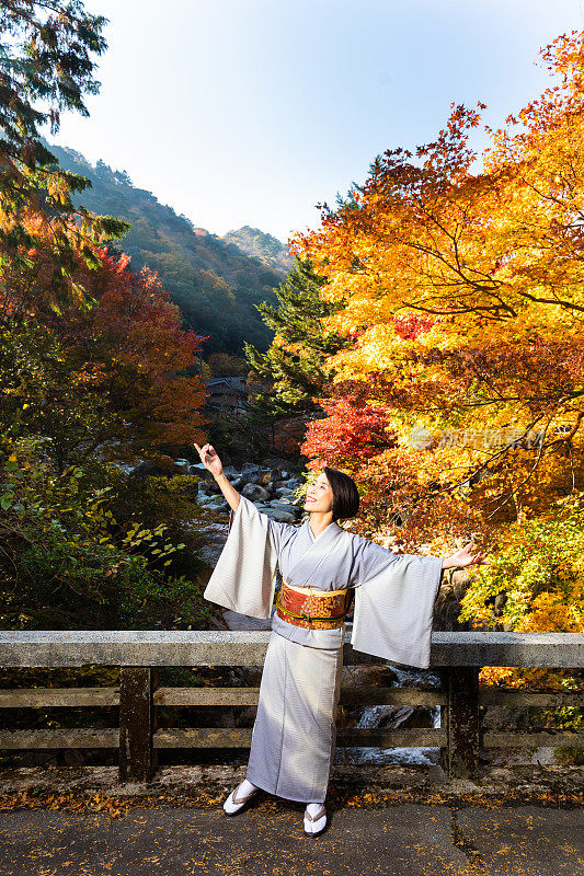 在小野的日本老年女子与秋天的枫叶跳舞