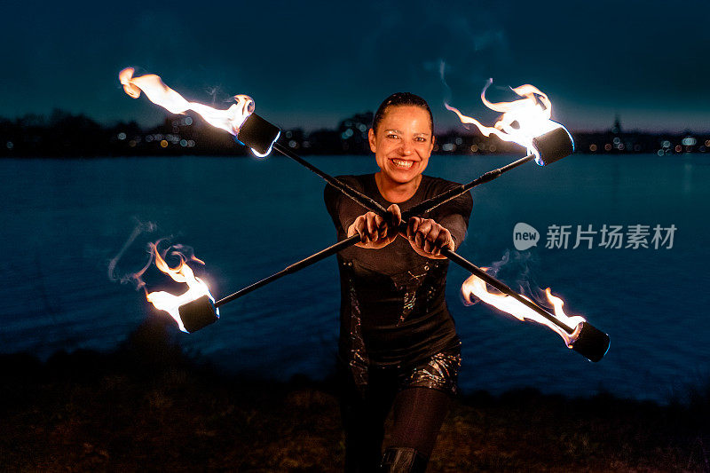 女火艺术家拿着燃烧的火炬在河边