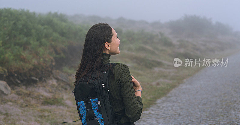 背着背包的年轻女子徒步旅行者在户外的山区旅行