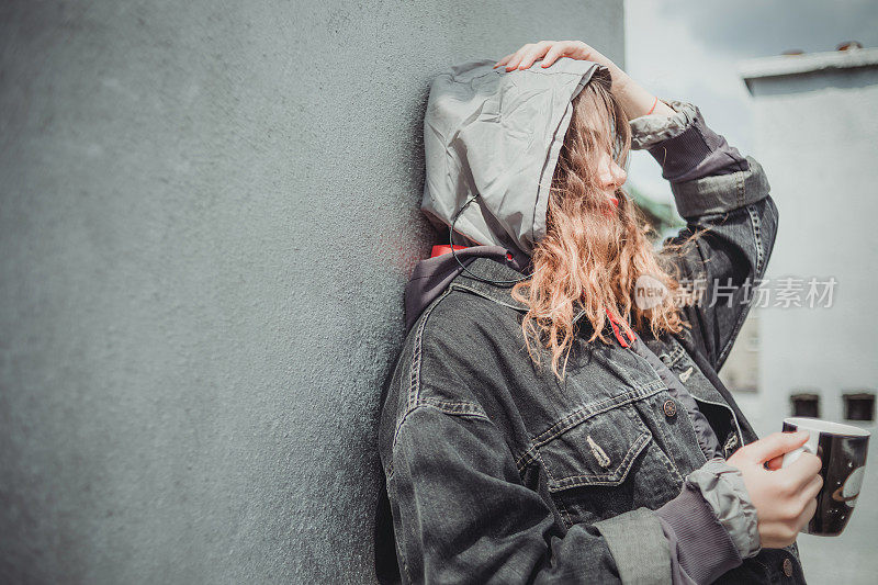 一个美丽的女孩，风的头发在建筑的屋顶享受自由和孤独。