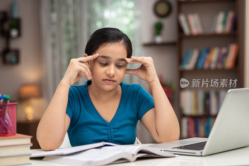 一个十几岁的女孩在家里学习的照片:-库存照片