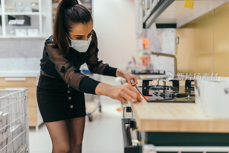 一位年轻女子在家具店购物时正在测量一件家具的尺寸