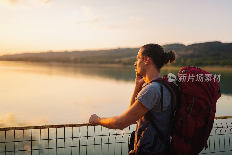 一个人在湖边悠闲地喝着啤酒，玩着智能手机