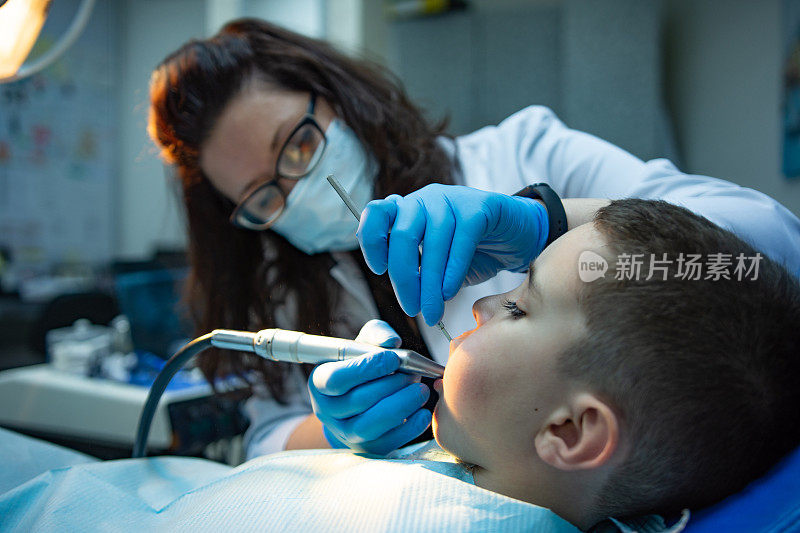 牙科医生为坐在牙科椅上的儿童检查牙齿