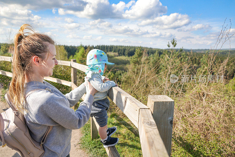 年轻的单身妈妈向她18个月大的女儿展示英格兰南部的森林景观。