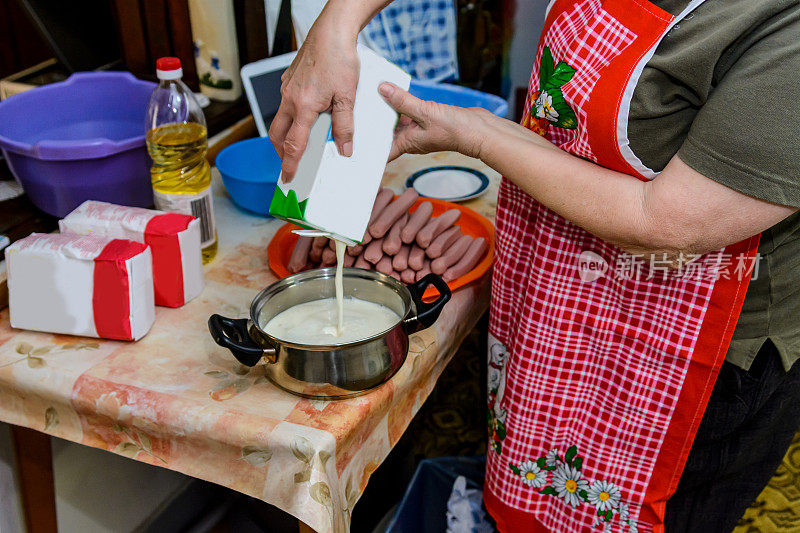 一位年长的妇女正在准备做香肠卷的面团。