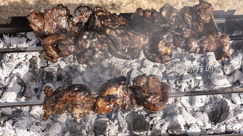 烤串的羊肉，烟雾缭绕，下面是炙热的煤炭