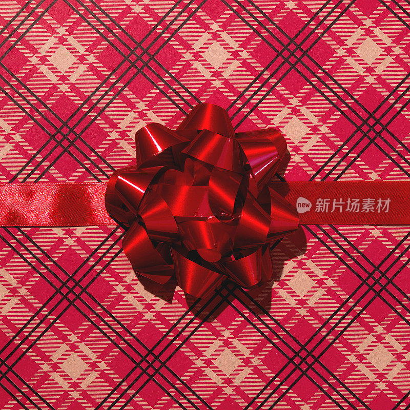 红色的礼品丝带和蝴蝶结在红色的工艺包装纸上