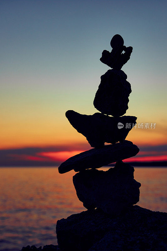 平衡的轮廓禅石在日落日出时间的海洋海滩。