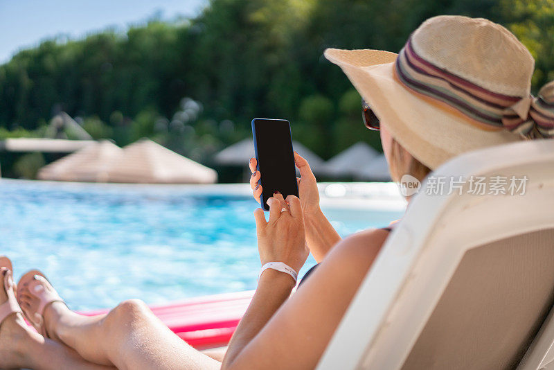 游泳池边的女人在用手机