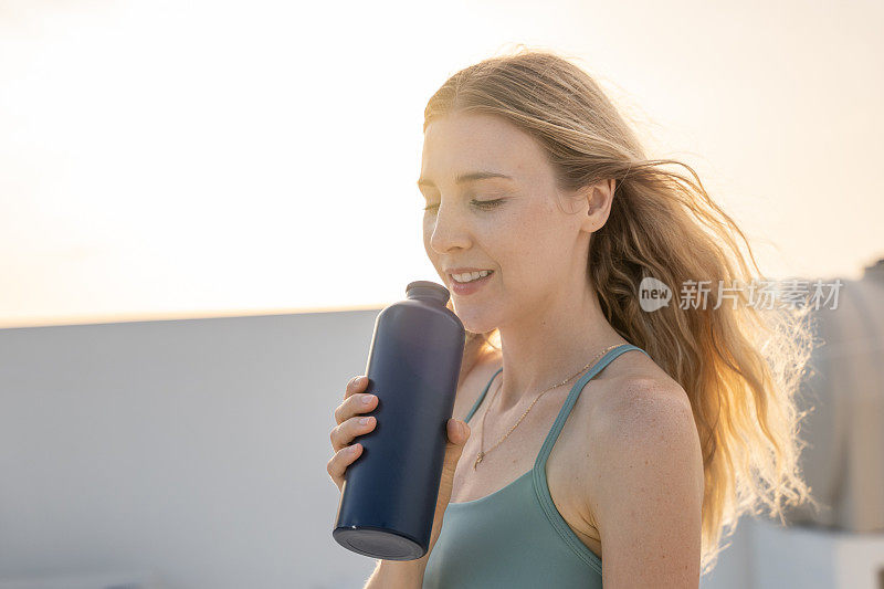 年轻女子用可重复使用的瓶子喝水的肖像