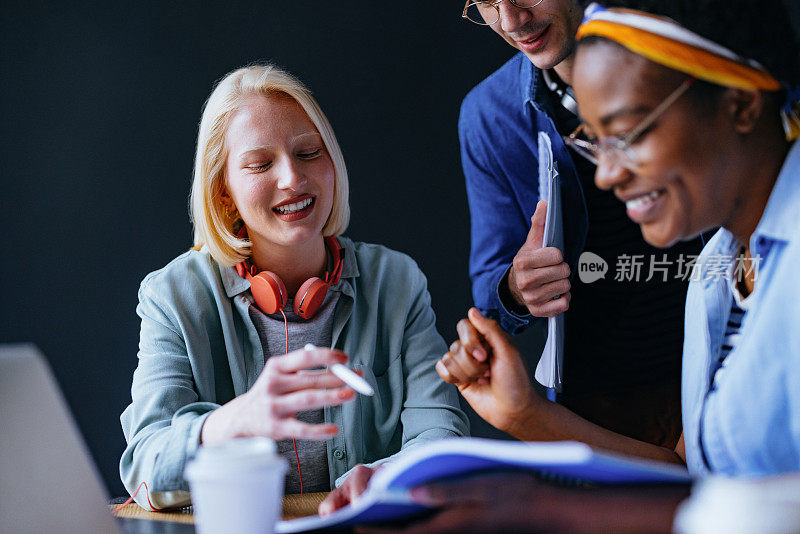 微笑的女人向她的朋友们解释新课程，同时一起在图书馆学习