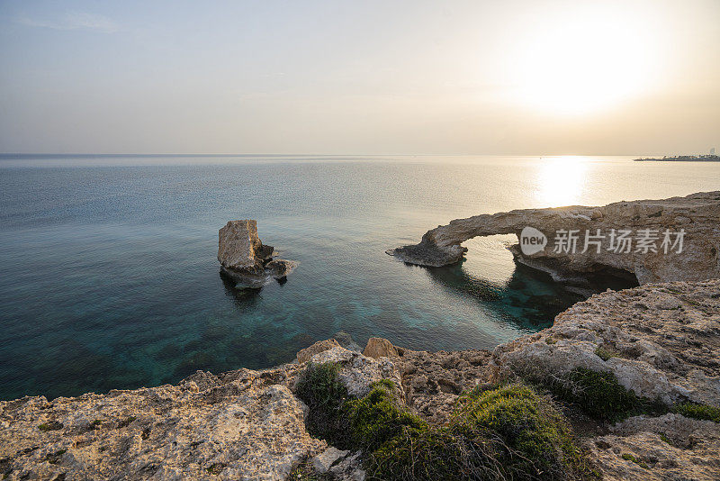 塞浦路斯阿伊亚纳帕附近的天然岩石拱门上美丽的日落。恋人之桥，地中海