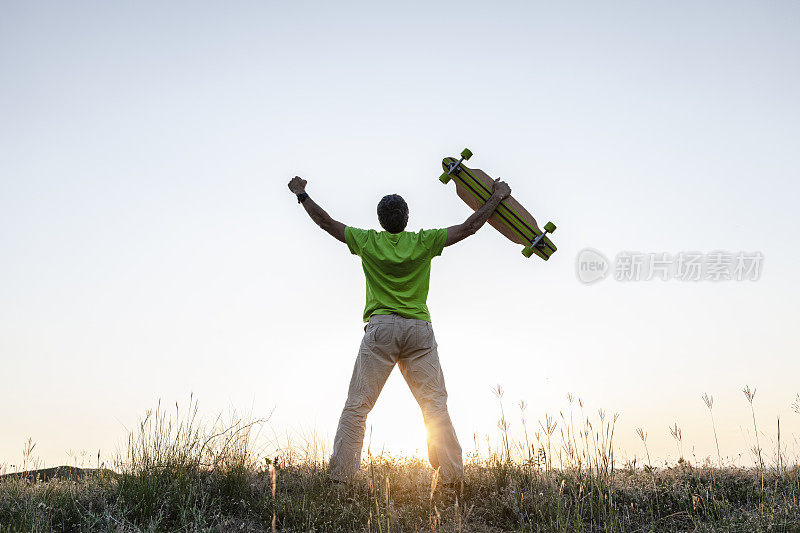 成熟的男人在自然的夕阳下，张开双臂。