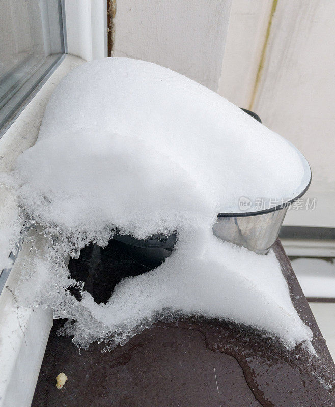 窗台上有一罐食物，上面盖着雪。