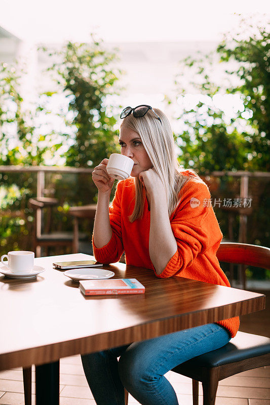 美丽的金发女人在咖啡馆喝咖啡