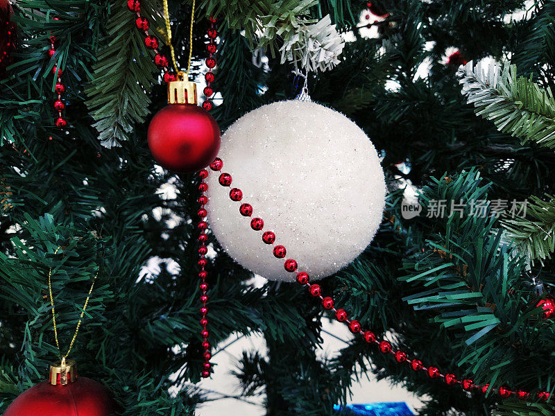 有装饰品、圣诞球和玩具的圣诞树。红白相间的挂饰。大大小小的小球，红红的珠子。