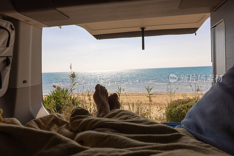 暑假期间，一名女子在沙滩上的露营车里放松