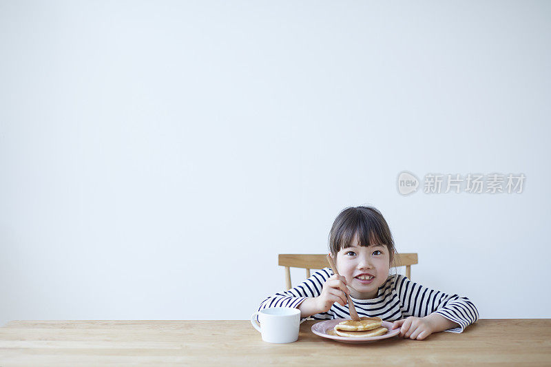 女孩在餐桌上吃煎饼