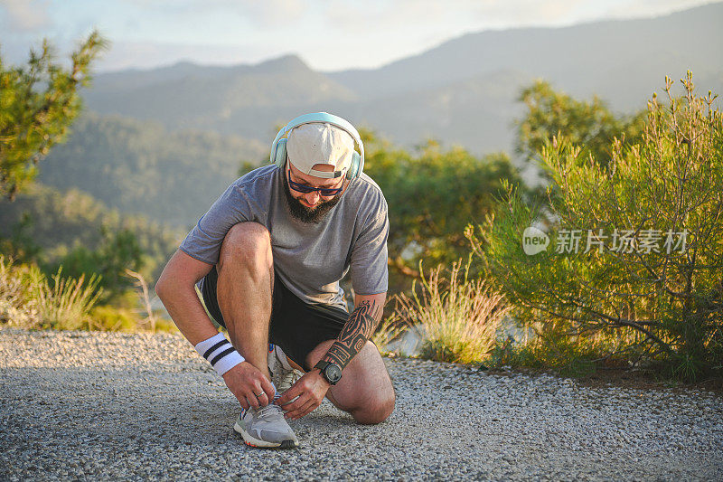 穿着运动服的男人沿着海边奔跑，可以看到群山