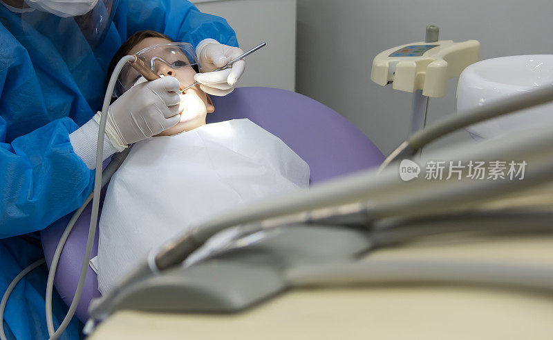 牙医坐在牙医椅上检查孩子的牙齿
