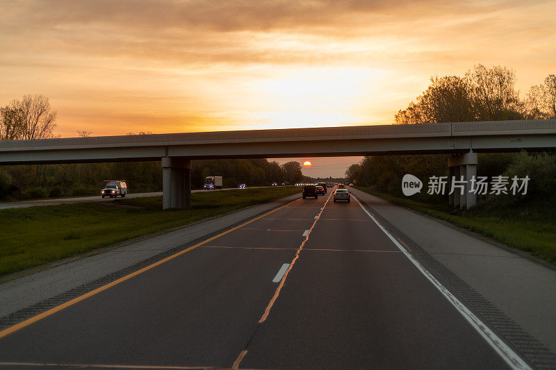 汽车在高速公路上行驶，背景是夕阳