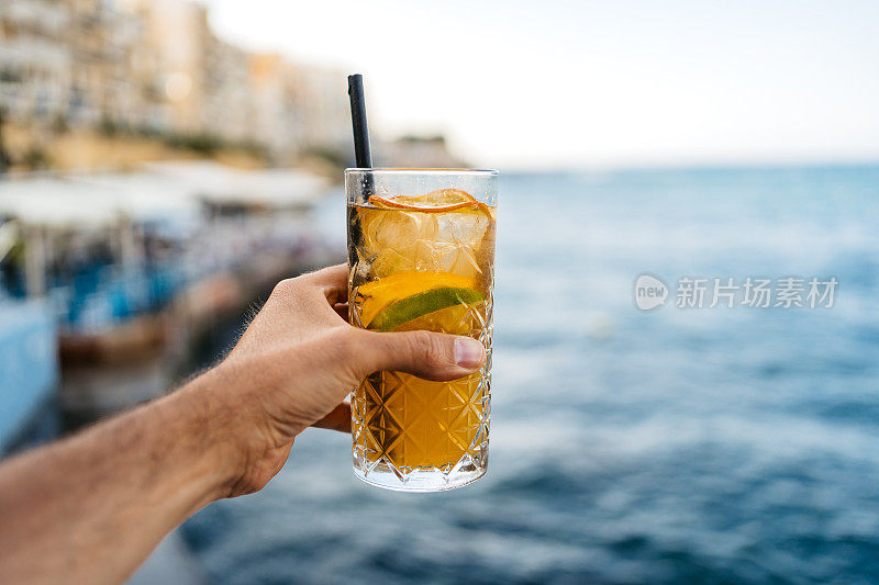 男子拿着姜汁柠檬鸡尾酒对着蓝海