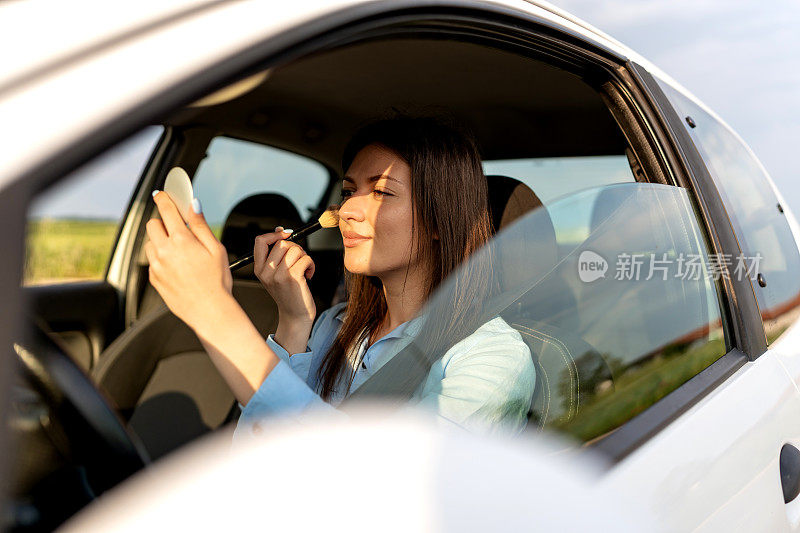 一位女士在车里为她的妆容做最后的修饰