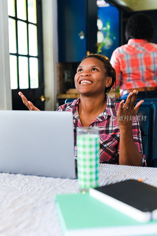 30多岁的黑人女性在家里使用她的笔记本电脑，得到好消息或在网上赢了东西，她感到兴奋和快乐