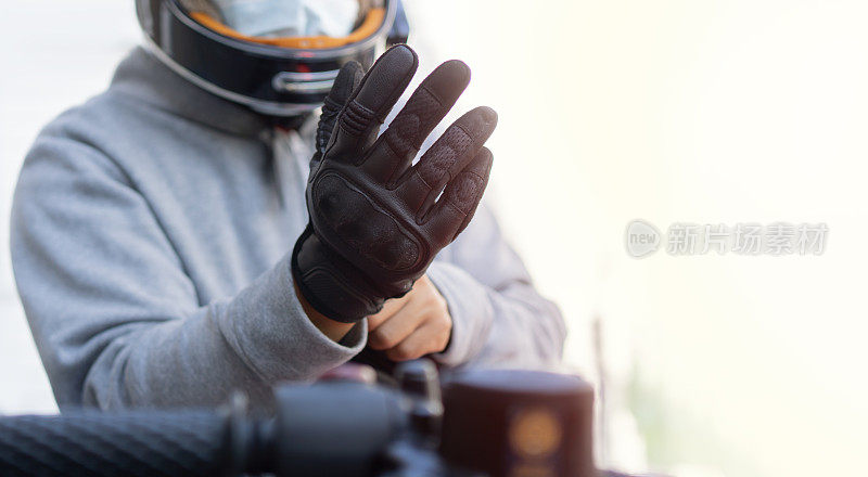 骑摩托车的人戴上皮手套驾驶他的摩托车。