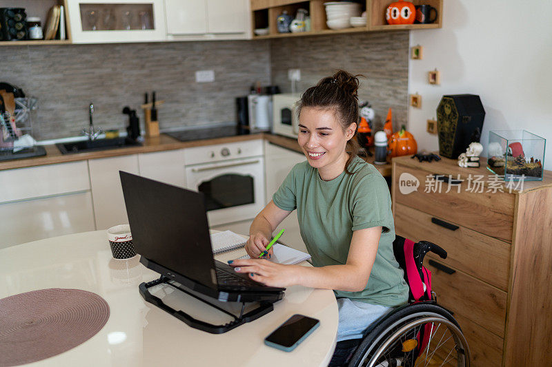 快乐的残疾女性在家用笔记本电脑工作。