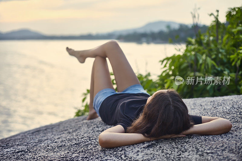 年轻女子在悬崖上放松，欣赏风景