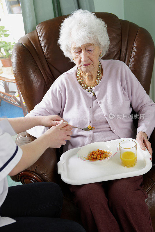 老年妇女在护士的帮助下吃饭
