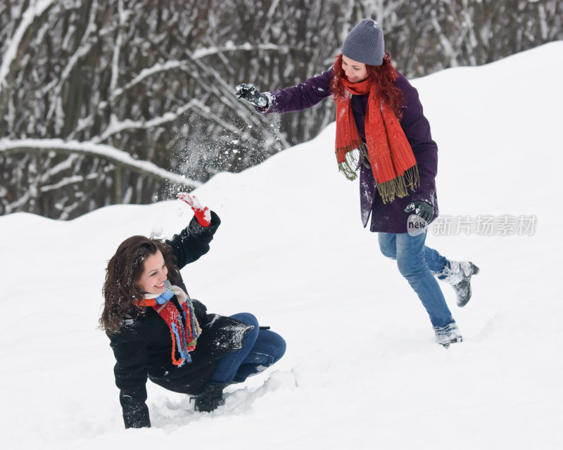 两个年轻女人在雪地上打雪仗