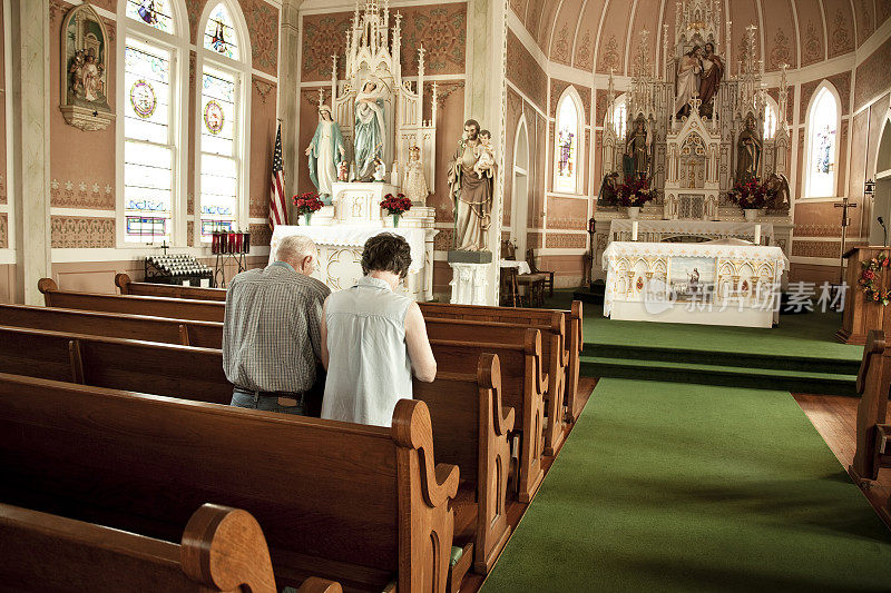 一对年长的男女在教堂里祈祷。
