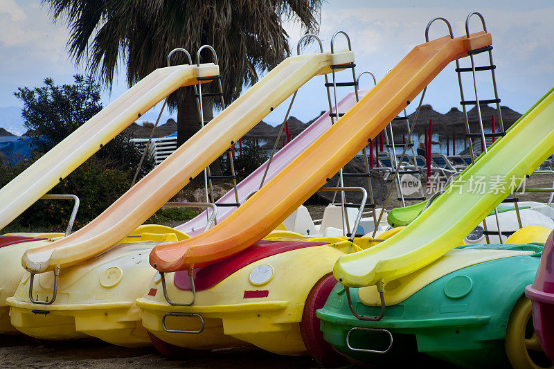 海滩上的一排带滑梯的脚踏船