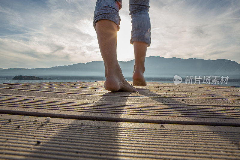 一个女人赤脚走在湖上的防波堤上