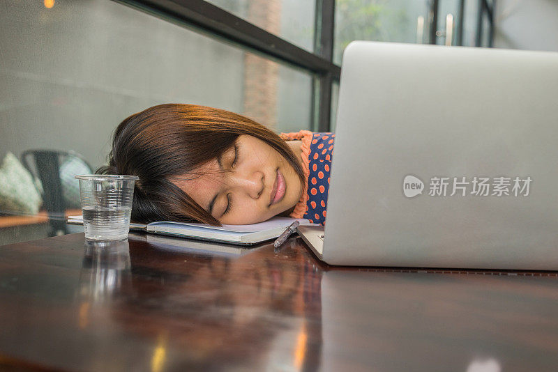 年轻的亚洲女孩在学习和使用笔记本电脑后睡觉