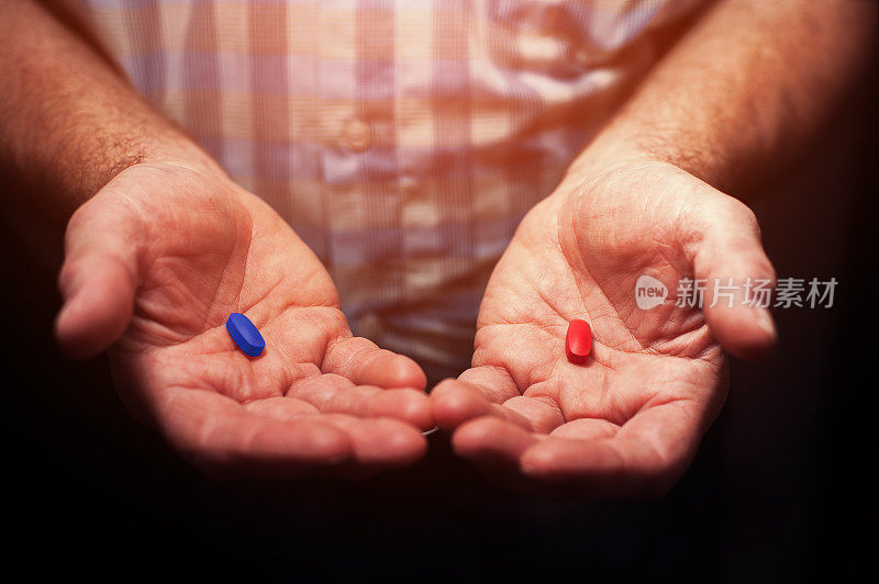 男性的手有红色和蓝色的药丸