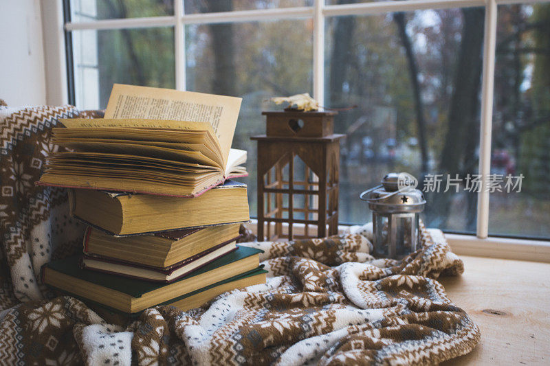 窗台上放着一堆书，上面盖着一条暖和的毯子