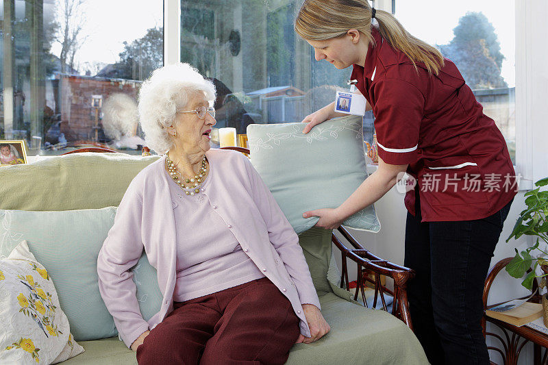 年轻的护士使老年妇女舒适的养老院